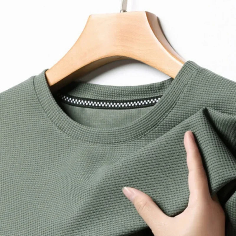 Mann trägt bequemes Kurzarm Herren T-Shirt mit atmungsaktiver Waffelstruktur in heller Farbe, Freizeitlook.