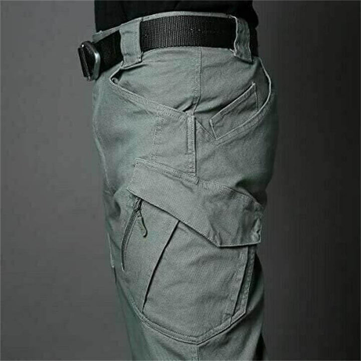Ein Mann trägt wasserdichte taktische Herrenhose beim Wandern im Wald, zeigt Komfort & Funktion.