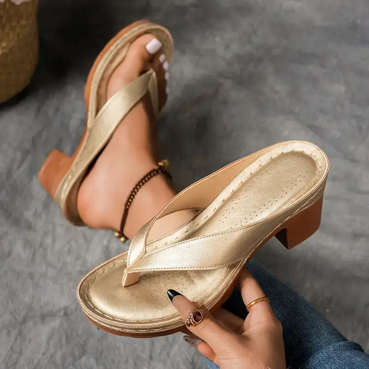 Damen Sandalen in Gold mit Absatz in der Hand gehalten