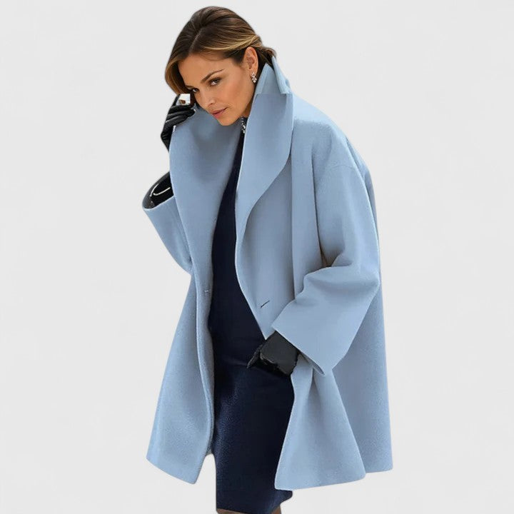 Frau trägt hellblauen Oversize-Mantel mit großem Kragen und eleganter Ausstrahlung.