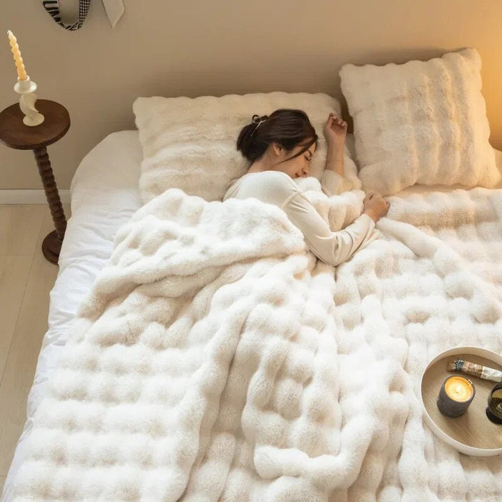 Frau schläft unter flauschiger, weißer Decke auf Bett mit Kissen, gemütliches Schlafzimmer.