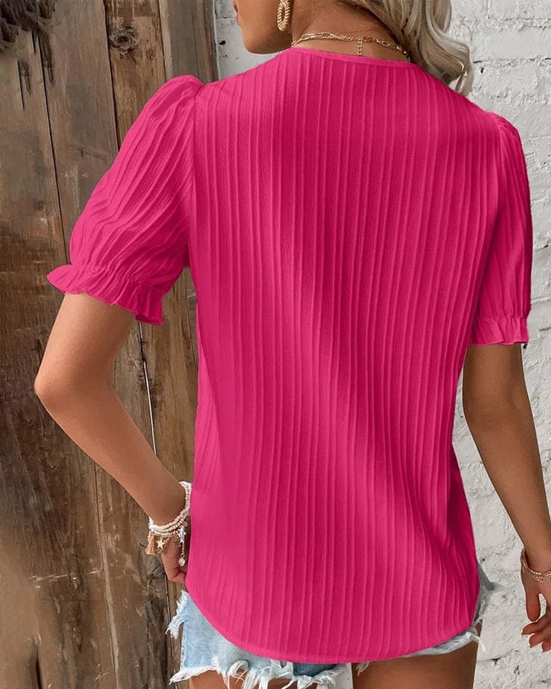 Junge Frau mit blonder Haartracht präsentiert die blaue Bluse, kombiniert mit Jeans, Hand in Tasche.