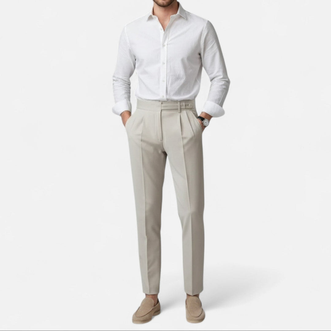 Mann trägt elegante beige Slim Fit Chino Hose und weißes Hemd, entspannte Pose.