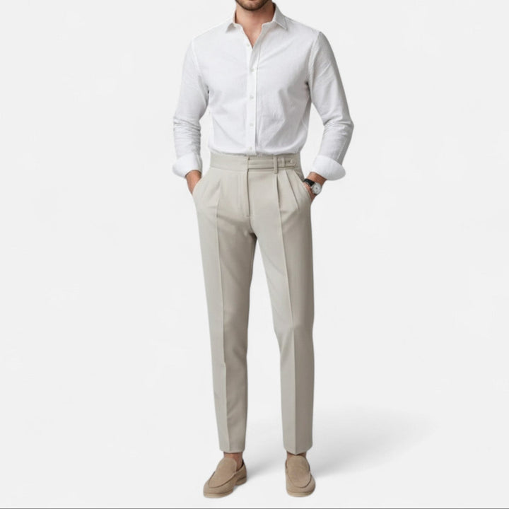 Mann trägt elegante beige Slim Fit Chino Hose und weißes Hemd, entspannte Pose.