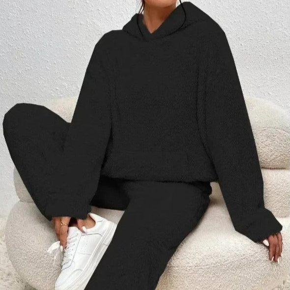 Frau entspannt auf dem Sofa im gemütlichen Damen Kuschel-Hoodie & Jogginghose Set. Perfekte Loungewear für Freizeit.