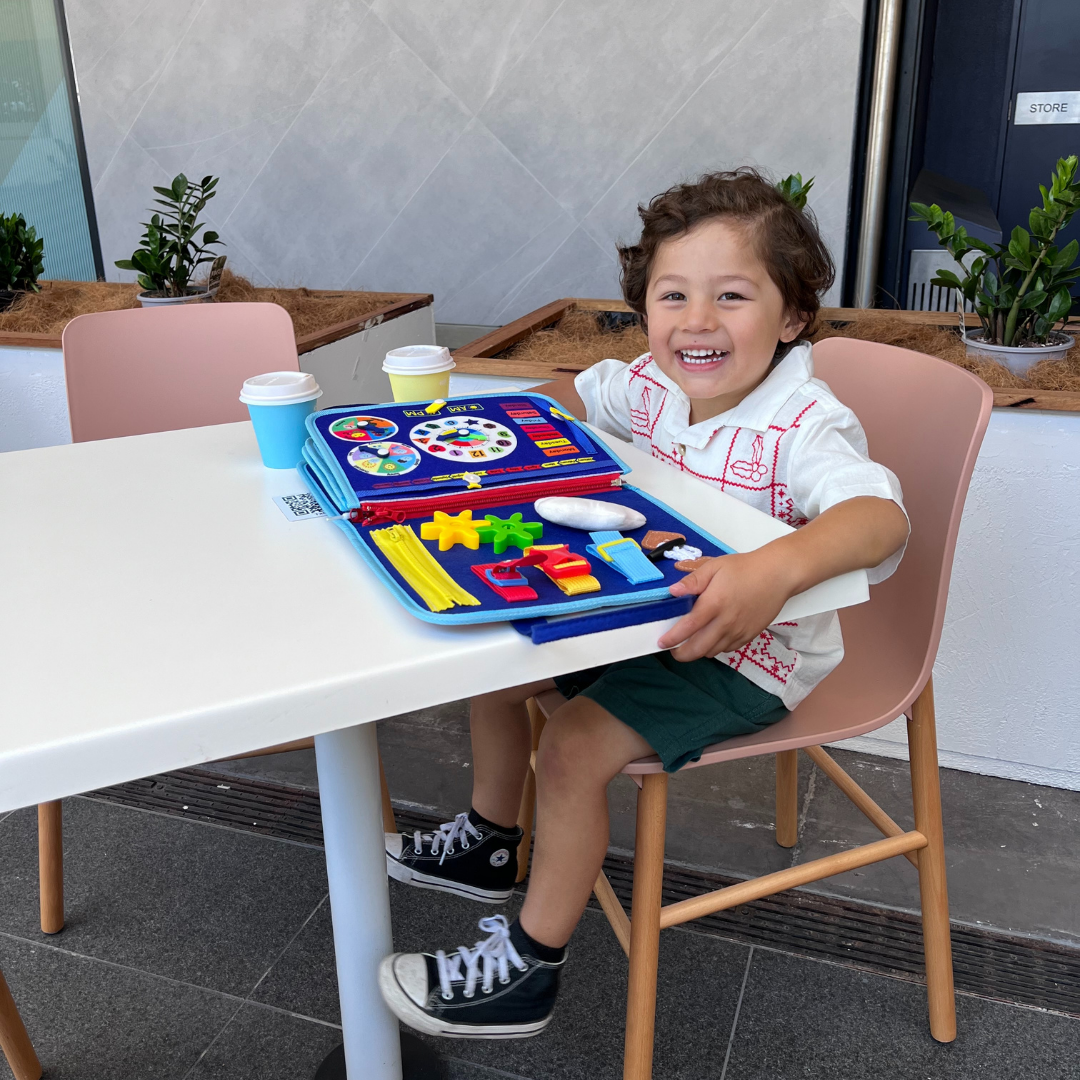 Kleinkind spielt mit farbenfrohem Montessori Beschäftigungsbrett, lernt spielerisch & fördert die Geschicklichkeit.