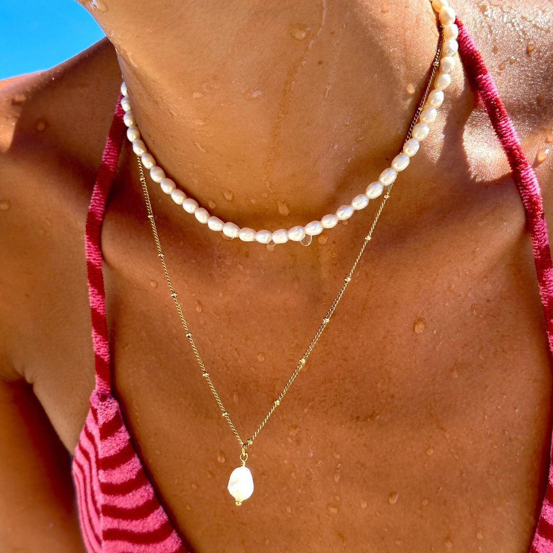 Stilvolles Damenschmuck Set aus glänzenden Goldketten und weißen Perlen