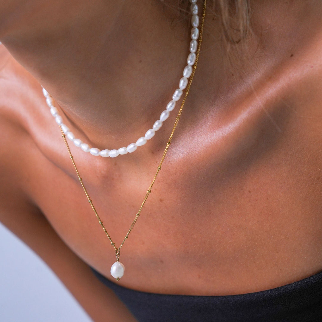 Damen Perlenkette kombiniert mit zarten Goldketten im angesagten Layering-Look