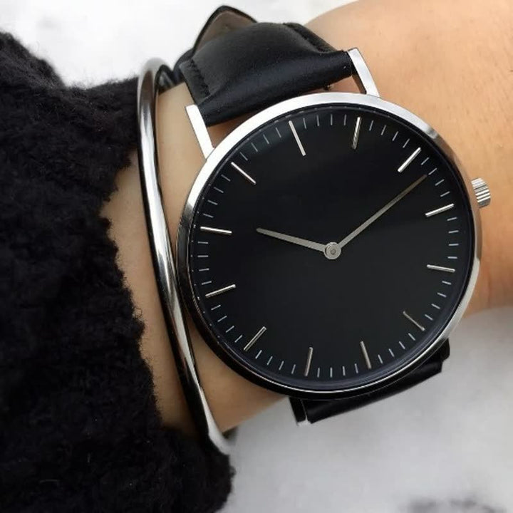 Schwarze Armbanduhr mit Lederarmband, minimalistisches Design, silbernes Gehäuse, Unisex.