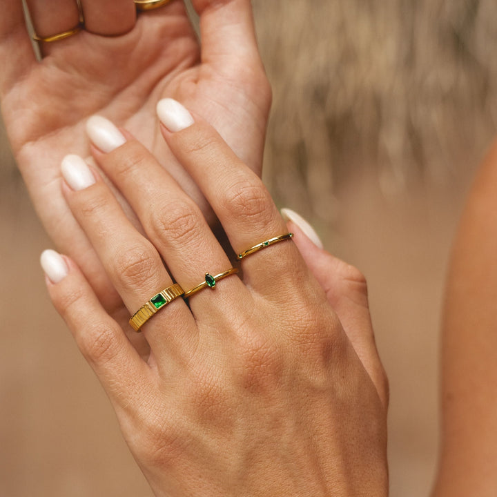Hand mit goldenem Chunky Ring und weiteren filigranen Ringen