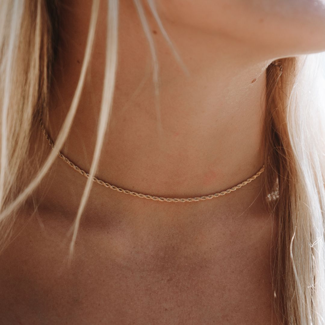 Detailaufnahme der goldenen Kordelkette am Hals