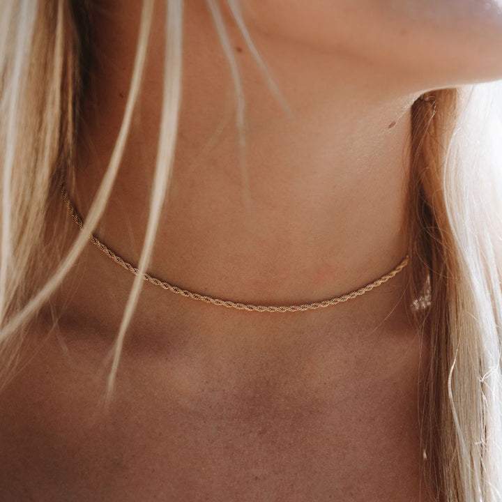 Detailaufnahme der goldenen Kordelkette am Hals