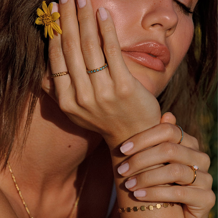 Minimalistischer Damenring in Gold mit türkisblauen Details am Finger