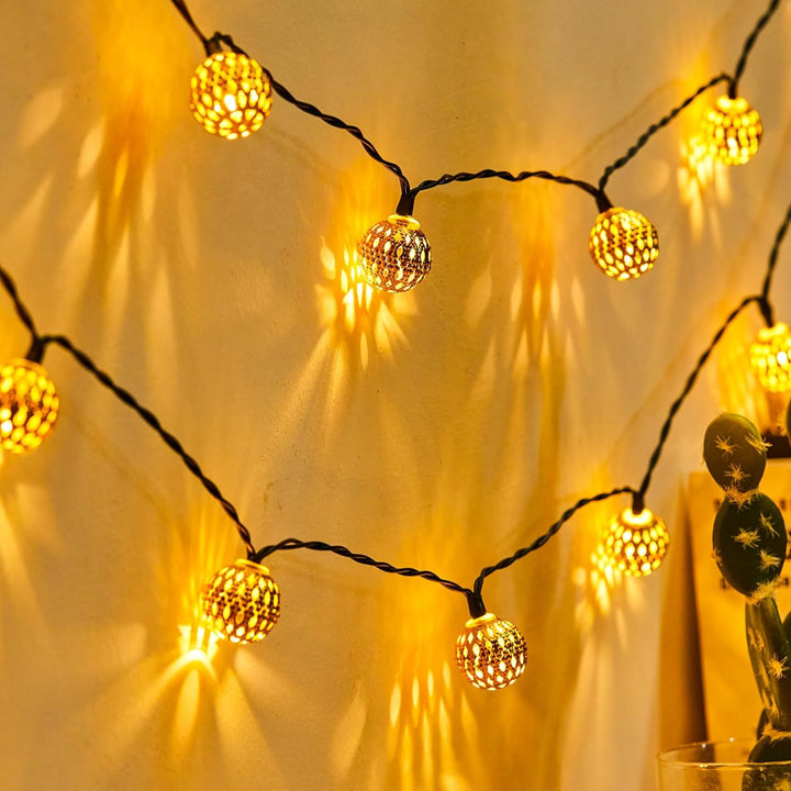 "Solarbetriebene Lichterkette mit marokkanischen, warmweiß leuchtenden Metallkugeln, ideal für die Gartenbeleuchtung."