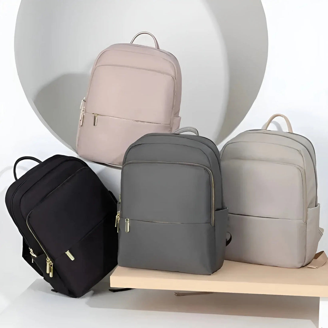 Vier moderne Rucksäcke in Schwarz, Grau, Beige und Creme auf Holzregal vor weißem Hintergrund.